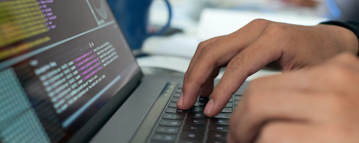 mains tapant sur un clavier avec du code pour assurer le support niveau 0 et 1