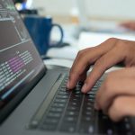mains tapant sur un clavier avec du code pour assurer le support niveau 0 et 1