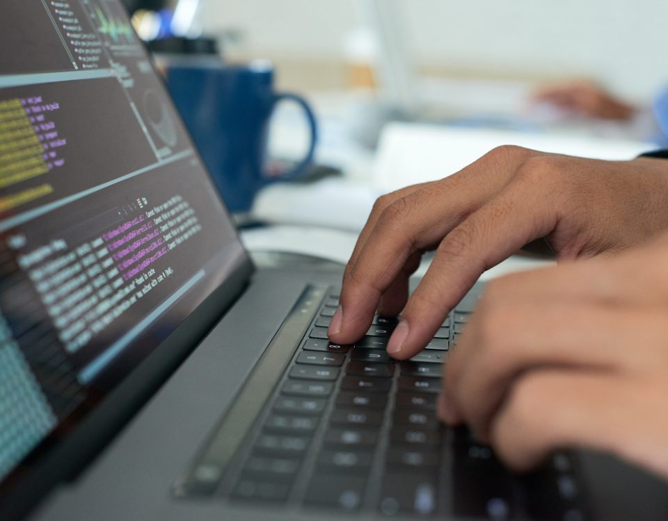 mains tapant sur un clavier avec du code pour assurer le support niveau 0 et 1